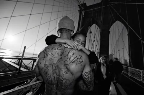 ZUN LEE Jerell carrying his son over the Brooklyn Bridge