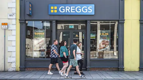 Getty Images People walk past a Greggs bakery