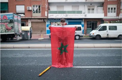 Getty Images Boy with a large Moroccan flag standing in the street.