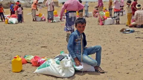 AFP/Getty Images Yemenis displaced by the conflict receive food aid. Photo: 29 March 2022