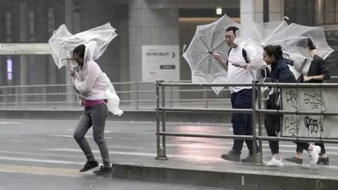 EPA Pedestrians in Tokyo struggle with umbrellas in the wind and rain