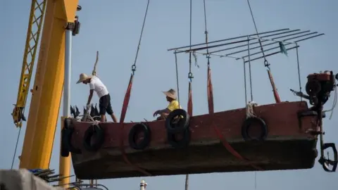 Getty Images Fishermen in China's Guangdong province remove their boat from the water in preparation for the arrival of Typhoon Mangkhut, 15 September 2018