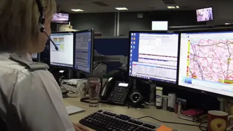 Northamptonshire Police Force control room with operator wearing headset and screens showing maps and other information
