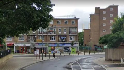 Google Street View image of shops and flats at a junction of Thessaly Road.