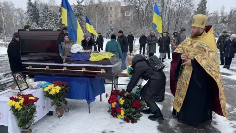 BBC/Ed Habershon Image of people gathered around a coffin at Denys Sosnenko's funeral