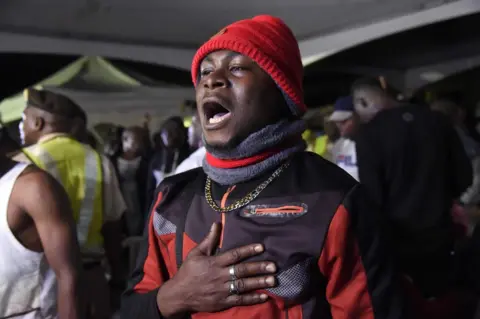 AFP A man, among a first group of Nigerians repatriated from South Africa following xenophobic violence, recites the national anthem after arriving in Lagos, on September 11, 2019.
