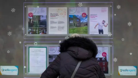 Getty Images Woman looks in estate agent's window