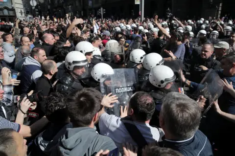 Reuters Protesters face riot police outside the residence of Serbian President Aleksandar Vucic in Belgrade. Photo: 17 March 2019
