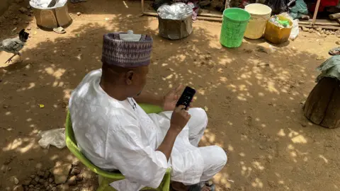 Gift Ufuoma/BBC Man looking at his phone