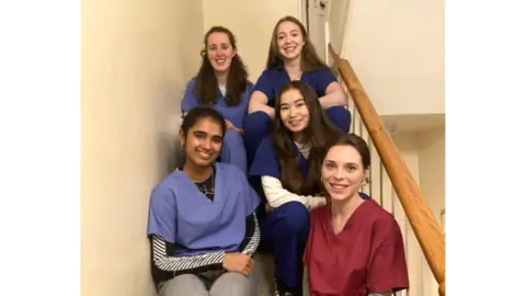 Bristol University  Five women dressed in scrubs sitting on the stairs