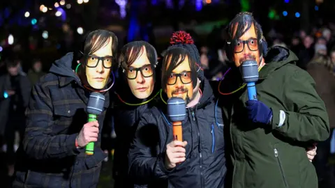 Reuters Four people wearing Jarvis Cocker masks pose