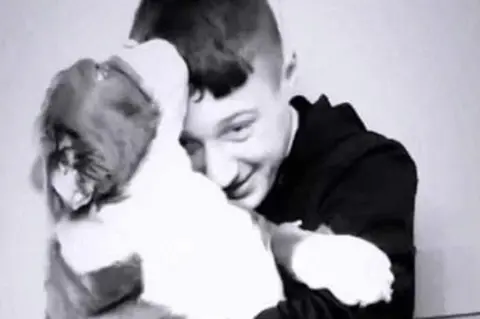Family handout Black and white picture of a boy cuddling a dog