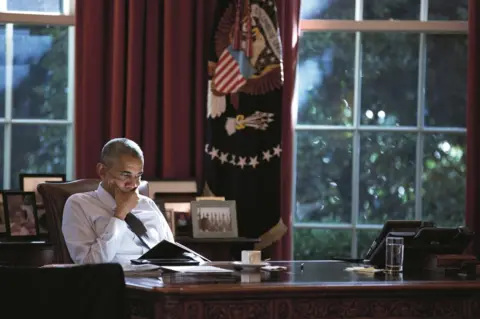 Pete Souza Obama sits at his desk