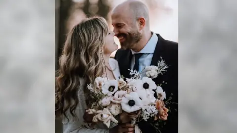 Oobaloos Photography A woman smiling up at a man in a wedding outfit