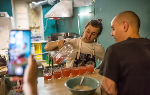 BBC Iiura serving drinks at the opening of his restaurant, Tempeh Time