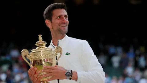Reuters Serbia's Novak Djokovic with the trophy as he celebrates winning the final against Switzerland's Roger Federer