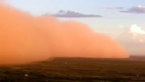 Orange dust cloud sweeping across ground