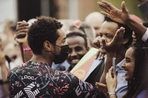 Getty Images Team Wanty's Eritrean rider Biniam Girmay Hailu celebrates with his fans before the start of the 105th Giro d'Italia 2022 in Visegrad, Hungary.