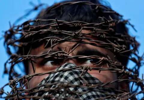 Danish Ismail / Reuters A masked Kashmiri man with his head covered with barbed wire attends a protest in Srinagar in October following the scrapping of the special constitutional status for Kashmir by the Indian government.