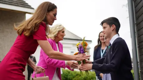 Reuters The Duchess and First Lady are given flowers by the children at the school
