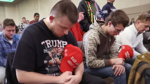 Trump supporters bow their heads in prayer at an Iowa campaign event