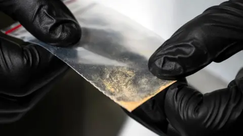 The Washington Post Gloved hands holding bag of drugs