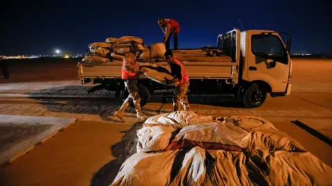 Reuters Three men load a truck with aid for Syria