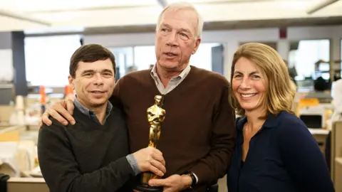 Getty Images The Boston Globe's Michael Rezendes, left, Walter V. Robinson, and Sacha Pfeiffer, right, hold Oscar winning writer Josh Singer's Oscar statue in the newsroom of the Boston Globe