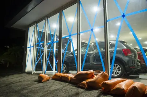 LIONEL CHAMOISEAU/AFP Car dealership windows are taped up.