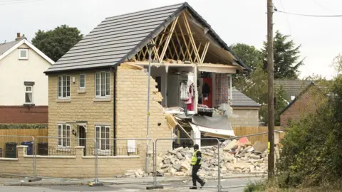 PA Damaged house with side of the property exposed showing clothes and contents; rubble on the ground outside