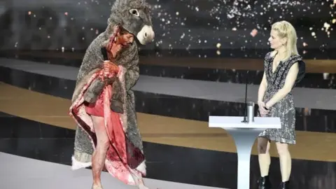 EPA French actress Corinne Masiero (left) wears a donkey costume on top of a bloodied dress in Paris, France. Photo: 12 March 2021