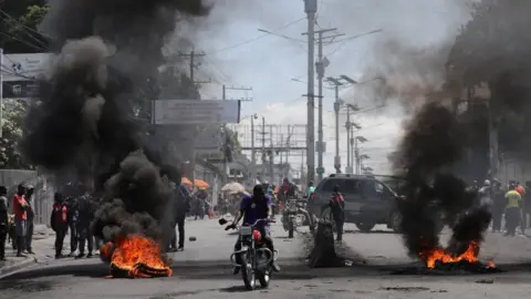 Reuters Motorists pass by a burning barricade in Port-au-Prince, Haiti