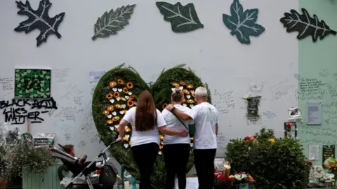 PA Media People pay their respects to 72 victims who died in the fire