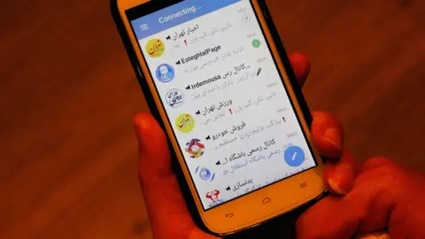 EPA An Iranian man shows his phone's social media app failing to connect in Tehran, Iran, 2 January 2018