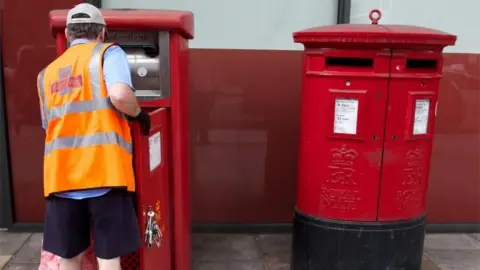 AFP Postman empties letter box