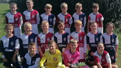 Steve Beale Children smiling as they pose for their football team photo
