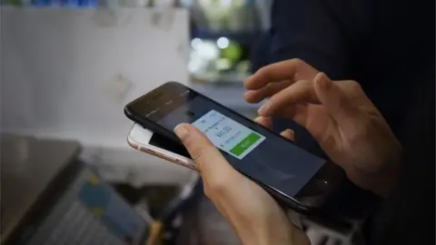 AFP Person makes a payment on their smartphone in China