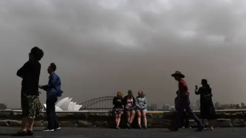 EPA Tourists in Sydney framed against a thick dust-filled sky