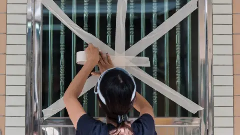 AFP A resident of a fishing village in Hong Kong tapes up her windows
