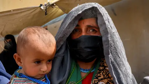 ELISE BLANCHARD/AFP via Getty Images In this picture taken on March 28, 2021, Farzana, who fled her village in Helmand province when it was taken over by the Taliban, waits to see a doctor at a mobile clinic for women and children set up at the residence of a local elder in Yarmuhamad village, near Lashkar Gah in Helmand province.