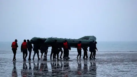 Reuters 40 migrants run on the beach with an inflatable dinghy, near Wimereux, France, 24 November 2021