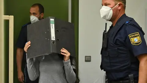 Getty Images Jennifer Wenisch in court, covering her face with a folder, 13 Oct 21