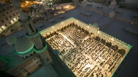 Getty Images Mosque at night full of people. It is a birds eye view of the mosque.