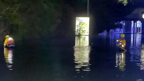 Firefighters in floodwater pumping it away