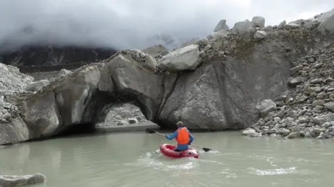 C. Scott Watson Scientist in a kayak assessing the melting glacier