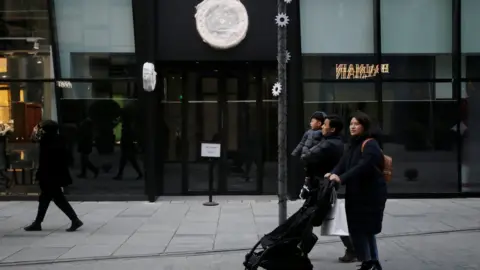 Reuters A family walk past a closed Canada Goose store in Beijing.