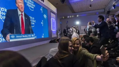 EPA Participants watch the appearance of US President Donald J. Trump on screen from an adjacent room, during the 48th Annual Meeting of the World Economic Forum (WEF) in Davos, Switzerland, 26 January 2018