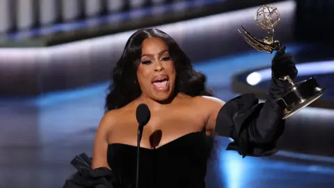 Niecy Nash-Betts holding an Emmy award