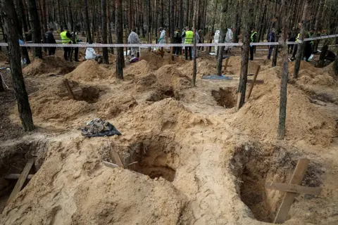 Gleb Garanich / Reuters Police and experts carry out exhumations at the scene of a mass burial in the town of Izyum, Kharkiv region, Ukraine, on 17 September 2022