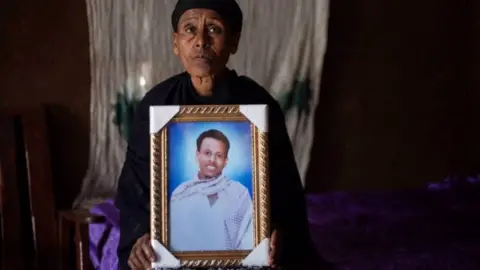 Getty Images Likitu Merdasa holds a portrait of her son Desta Garuma, a 27-year-old rickshaw driver, allegedly killed by security forces, while at her home in Nekemte, West Oromia, on February 26, 2020